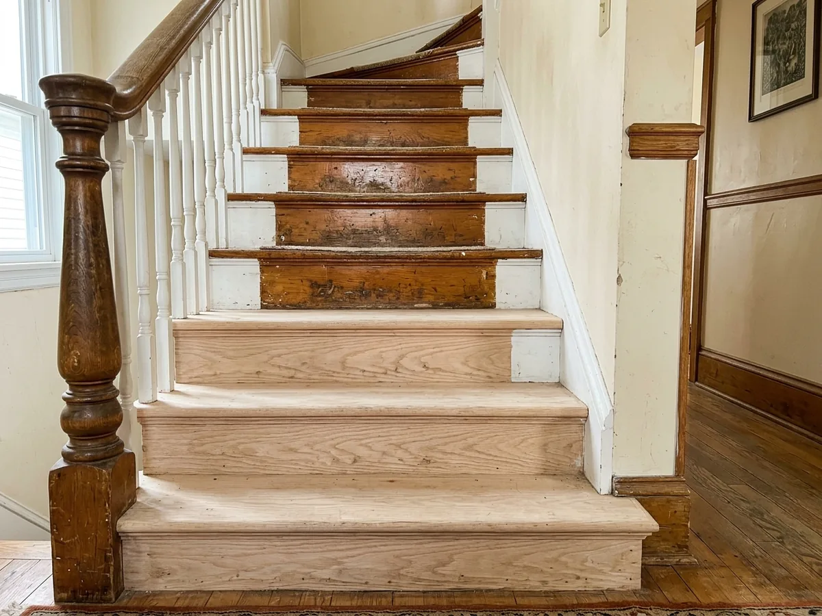 Staircase with oak treads half sanded and half still covered in worn finish